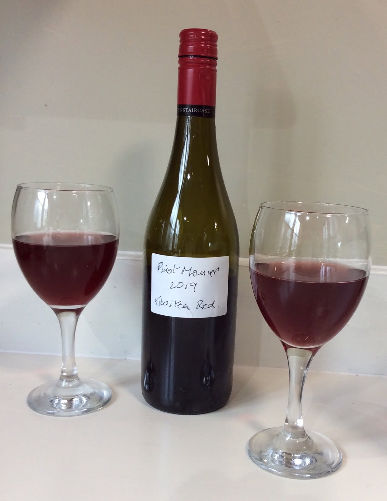A bottle of home-made Kiwitea Red beside two glasses of red wine