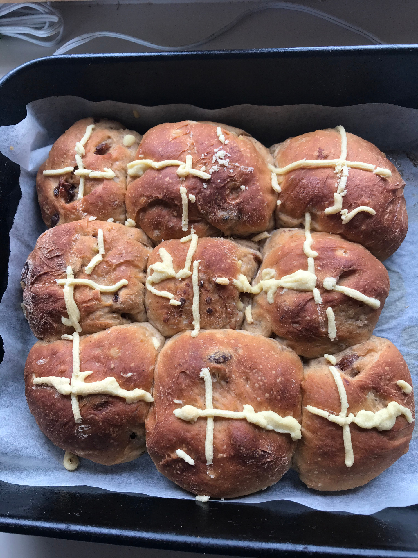 A tray of home-baked hot cross buns fresh from the oven