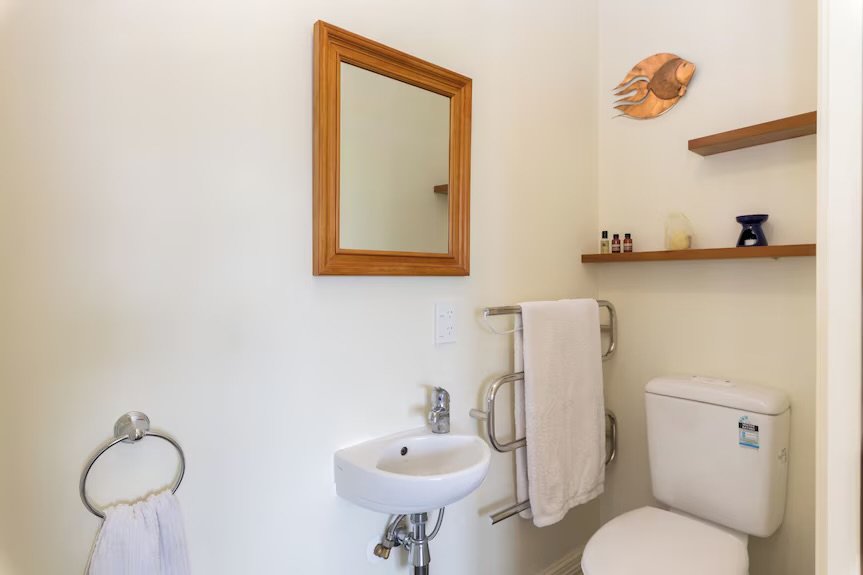 Bathroom of the self-contained apartment with a vanity, mirror and heated towel rail