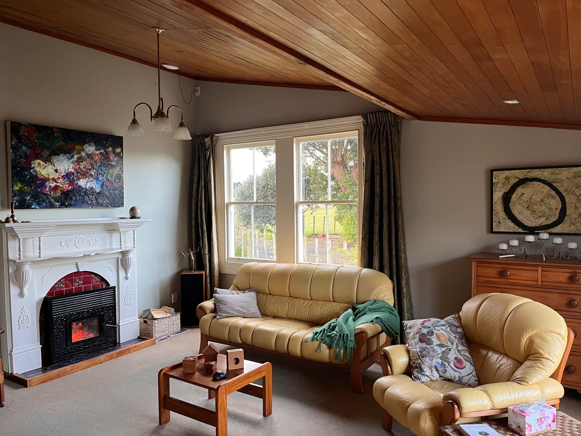 Lounge with a white mantel fireplace, timber-panelled ceiling and a yellow leather sofa