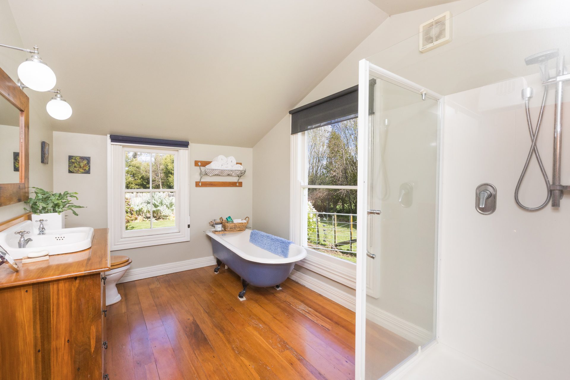 Bathroom with a freestanding clawfoot bathtub, timber floors and a garden view