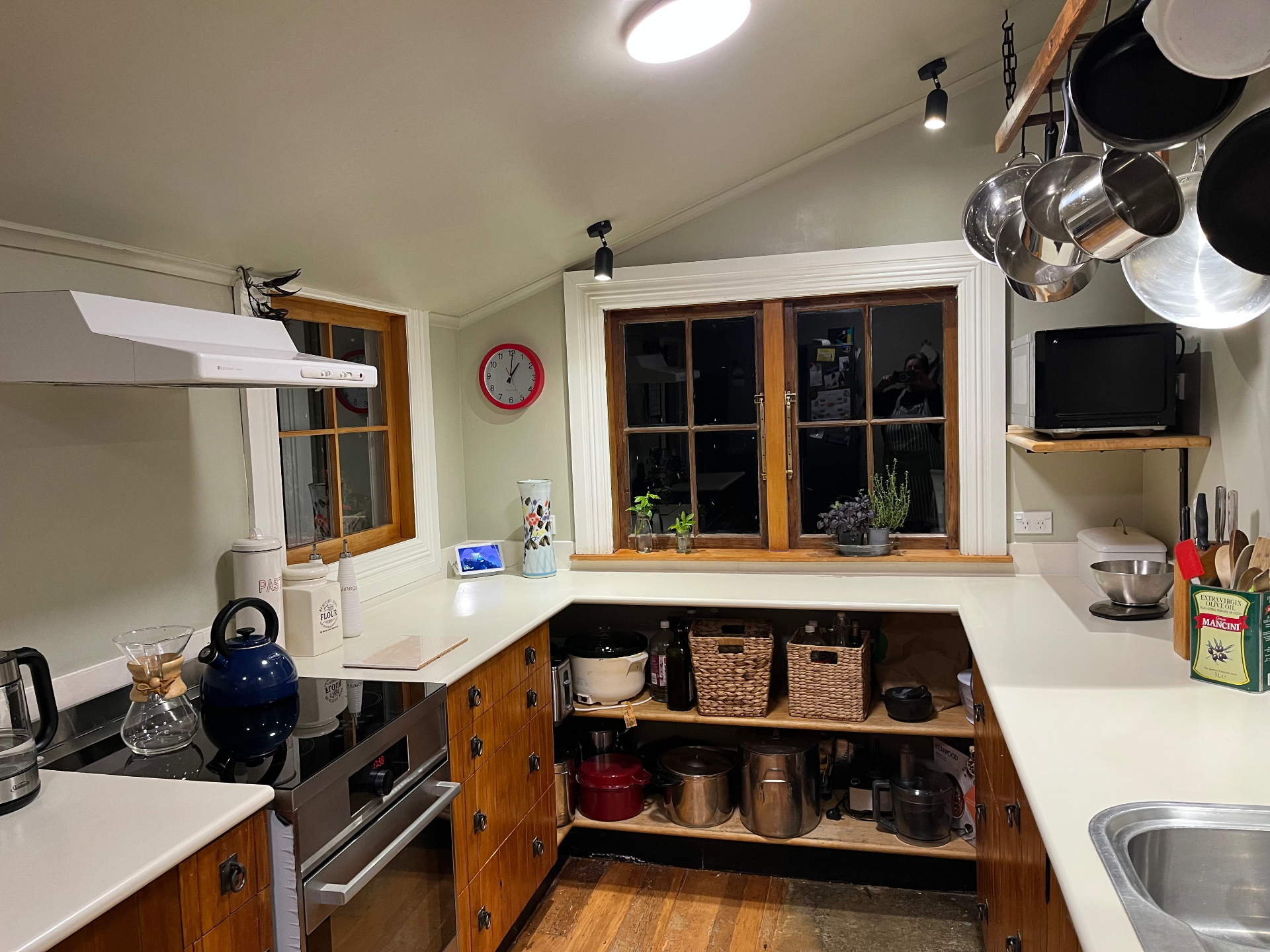 Wide view of the farmhouse kitchen with rimu cabinetry, hanging pot rack and vaulted ceiling