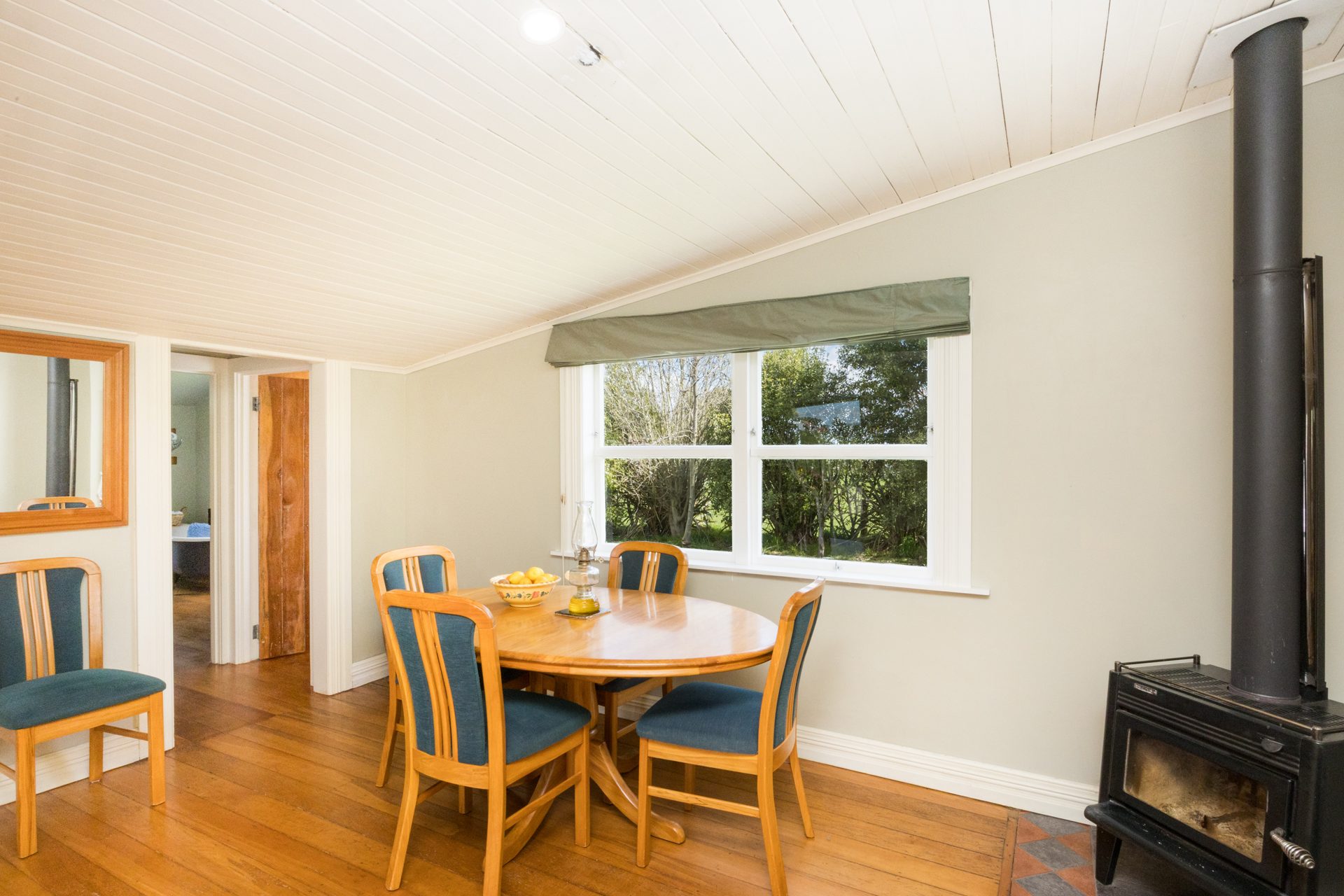 Dining room with a freestanding black wood burner, timber floors and a round dining table