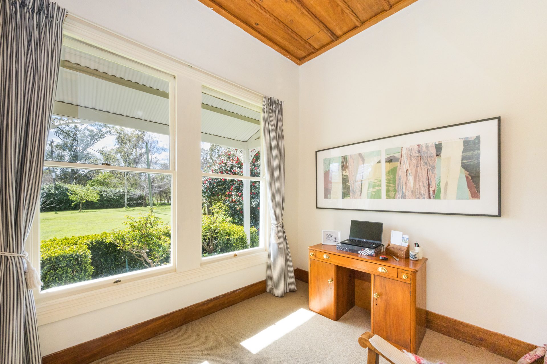 Home study with a desk, bookshelves and a wide window overlooking the garden