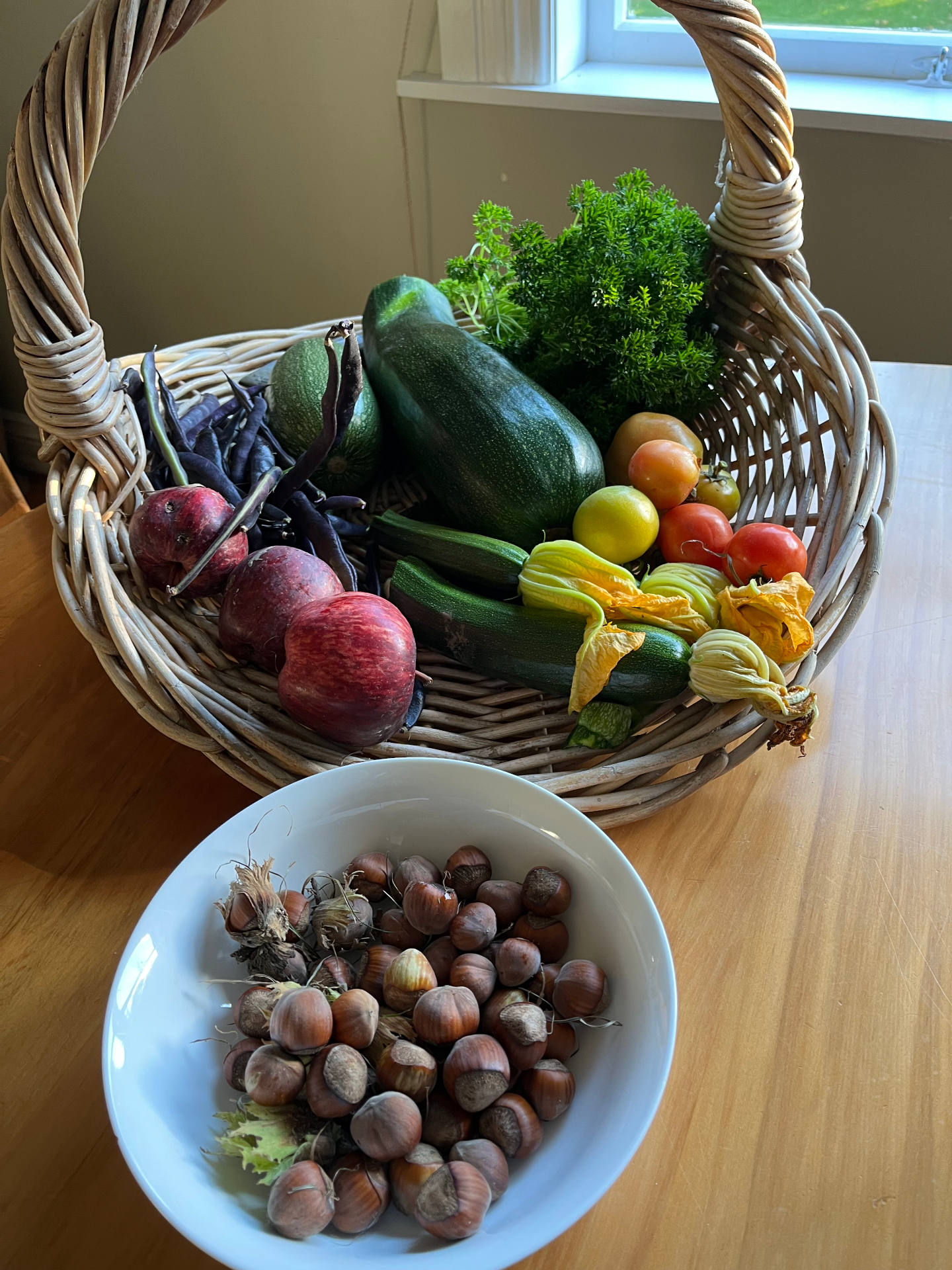 A basket of freshly picked vegetables and a bowl of hazelnuts