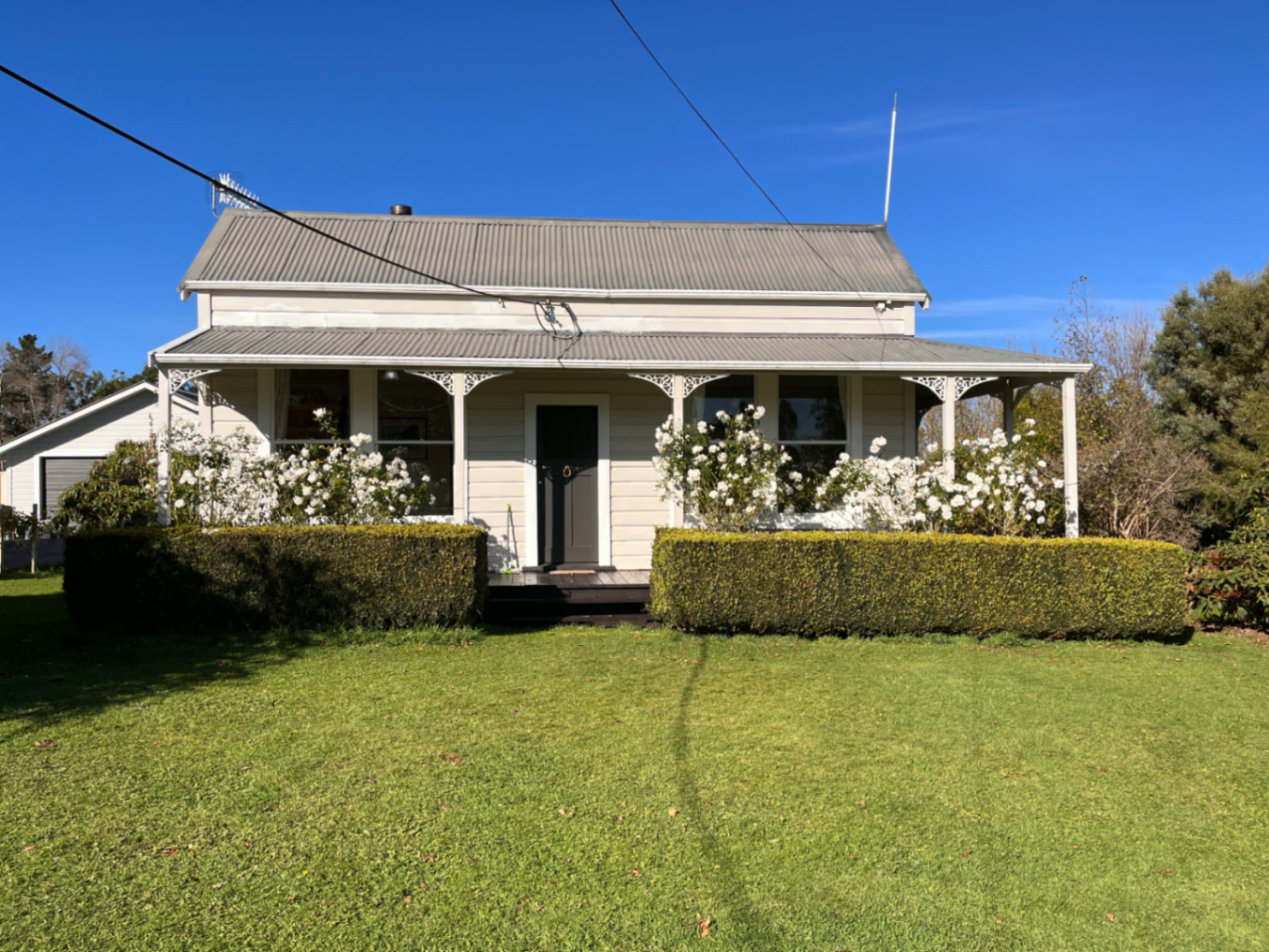 The farmhouse at 2114 Kimbolton Road with roses and a wide veranda